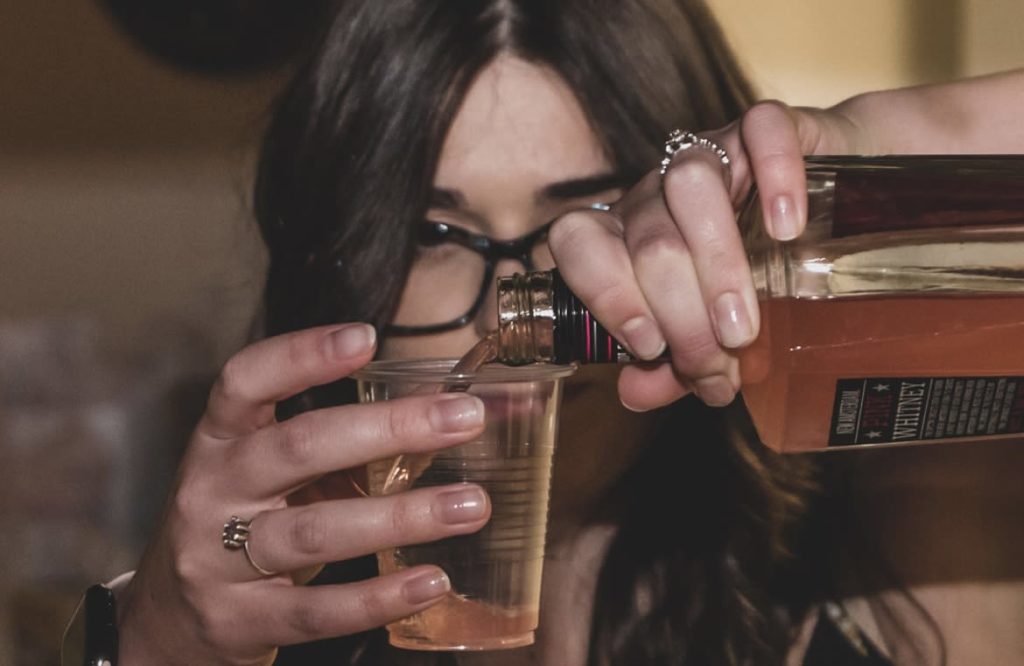 Hailey from The EventTender looking seriously at a glass as she pours a shot for a wedding guest.
