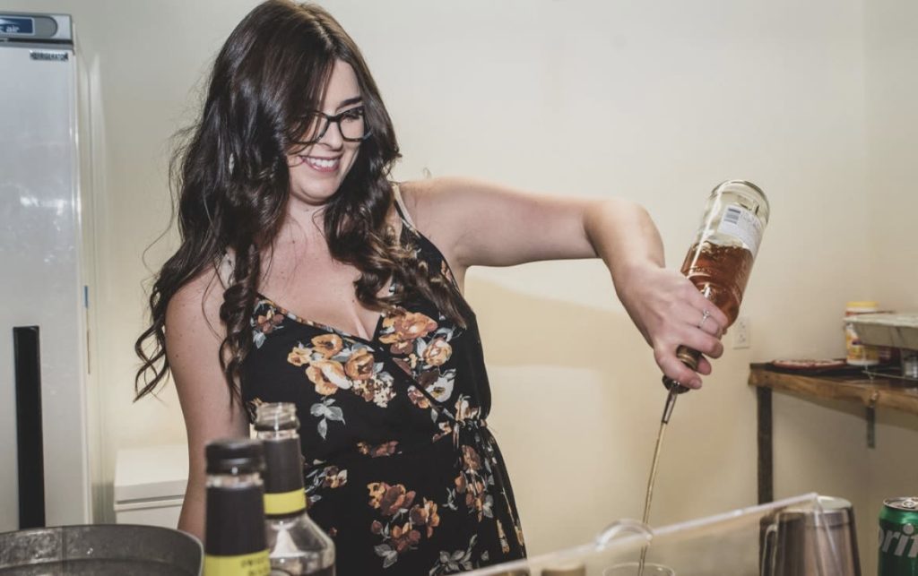 Hailey from The EventTender smiling as she pours a drink for a wedding guest.