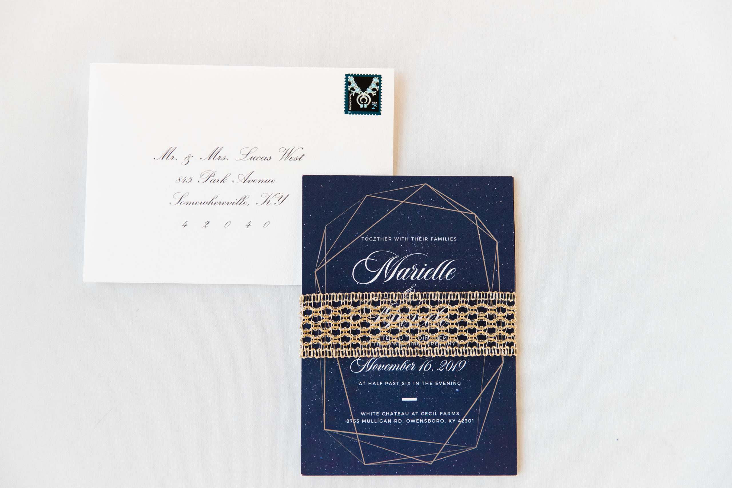 Navy celestial wedding invitation with a gold braided belly band and stamped white envelope.